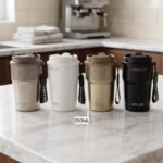 Four 350ml LYLEE insulated travel coffee mugs in taupe, white, olive green, and matte black lined up on a marble countertop.