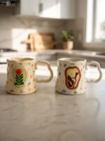 Handcrafted cream ceramic coffee mug featuring hand-painted botanical flower artwork, a scalloped rim, and an ergonomic wavy handle sitting on a marbleHandcrafted cream ceramic coffee mug featuring hand-painted botanical flower artwork, a scalloped rim, and an ergonomic wavy handle sitting on a marble countertop.Handcrafted cream ceramic coffee mug featuring hand-painted botanical flower artwork, a scalloped rim, and an ergonomic wavy handle sitting on a marble countertop.Handcrafted cream ceramic coffee mug featuring hand-painted botanical flower artwork, a scalloped rim, and an ergonomic wavy handle sitting on a marble countertop.Handcrafted cream ceramic coffee mug featuring hand-painted botanical flower artwork, a scalloped rim, and an ergonomic wavy handle sitting on a marble countertop.Handcrafted cream ceramic coffee mug featuring hand-painted botanical flower artwork, a scalloped rim, and an ergonomic wavy handle sitting on a marble countertop.Handcrafted cream ceramic coffee mug featuring hand-painted botanical flower artwork, a scalloped rim, and an ergonomic wavy handle sitting on a marble countertop.Handcrafted cream ceramic coffee mug featuring hand-painted botanical flower artwork, a scalloped rim, and an ergonomic wavy handle sitting on a marble countertop.Handcrafted cream ceramic coffee mug featuring hand-painted botanical flower artwork, a scalloped rim, and an ergonomic wavy handle sitting on a marble countertop.Handcrafted cream ceramic coffee mug featuring hand-painted botanical flower artwork, a scalloped rim, and an ergonomic wavy handle sitting on a marble countertop.Handcrafted cream ceramic coffee mug featuring hand-painted botanical flower artwork, a scalloped rim, and an ergonomic wavy handle sitting on a marble countertop.Handcrafted cream ceramic coffee mug featuring hand-painted botanical flower artwork, a scalloped rim, and an ergonomic wavy handle sitting on a marble countertop.Handcrafted cream ceramic coffee mug featuring hand-painted botanical flower artwork, a scalloped rim, and an ergonomic wavy handle sitting on a marble countertop.Handcrafted cream ceramic coffee mug featuring hand-painted botanical flower artwork, a scalloped rim, and an ergonomic wavy handle sitting on a marble countertop.Handcrafted cream ceramic coffee mug featuring hand-painted botanical flower artwork, a scalloped rim, and an ergonomic wavy handle sitting on a marble countertop.Handcrafted cream ceramic coffee mug featuring hand-painted botanical flower artwork, a scalloped rim, and an ergonomic wavy handle sitting on a marble countertop.Handcrafted cream ceramic coffee mug featuring hand-painted botanical flower artwork, a scalloped rim, and an ergonomic wavy handle sitting on a marble countertop.Handcrafted cream ceramic coffee mug featuring hand-painted botanical flower artwork, a scalloped rim, and an ergonomic wavy handle sitting on a marble countertop.Handcrafted cream ceramic coffee mug featuring hand-painted botanical flower artwork, a scalloped rim, and an ergonomic wavy handle sitting on a marble countertop.Handcrafted cream ceramic coffee mug featuring hand-painted botanical flower artwork, a scalloped rim, and an ergonomic wavy handle sitting on a marble countertop.Handcrafted cream ceramic coffee mug featuring hand-painted botanical flower artwork, a scalloped rim, and an ergonomic wavy handle sitting on a marble countertop.Handcrafted cream ceramic coffee mug featuring hand-painted botanical flower artwork, a scalloped rim, and an ergonomic wavy handle sitting on a marble countertop.Handcrafted cream ceramic coffee mug featuring hand-painted botanical flower artwork, a scalloped rim, and an ergonomic wavy handle sitting on a marble countertop.Handcrafted cream ceramic coffee mug featuring hand-painted botanical flower artwork, a scalloped rim, and an ergonomic wavy handle sitting on a marble countertop.Handcrafted cream ceramic coffee mug featuring hand-painted botanical flower artwork, a scalloped rim, and an ergonomic wavy handle sitting on a marble countertop.Handcrafted cream ceramic coffee mug featuring hand-painted botanical flower artwork, a scalloped rim, and an ergonomic wavy handle sitting on a marble countertop. countertop.