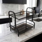 2-tier black metal dish drying rack with utensil holder and drip tray on a marble kitchen countertop
