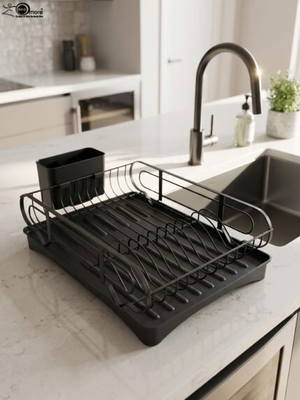 Matte black metal dish drying rack with attached utensil holder and drip tray sitting on a marble kitchen countertop beside a sink.