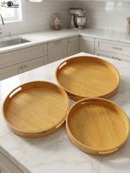 Three round natural wooden serving trays with cutout handles arranged on a marble kitchen countertop.