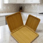 Set of 3 natural wooden square serving trays in small, medium, and large sizes displayed on a marble kitchen countertop.