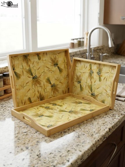 Set of three light wood rectangular serving trays featuring a golden wheat sheath pattern and built-in side handles displayed on a kitchen counter.