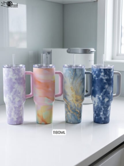 Four 1180ml insulated stainless steel travel tumblers with handles and straws in lavender, peach, blue-gold, and navy marble patterns on a kitchen counter.