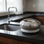 An elegant champagne-colored insulated luxury hotpot casserole with a sparkling crystal rhinestone base and chrome accents, sitting on a dark kitchen countertop.