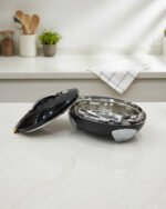Glossy black insulated stainless steel hotpot casserole with silver chrome accents and lid open on a kitchen countertop.