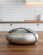 Modern grey insulated hotpot casserole with polished chrome handle on a wooden kitchen countertop