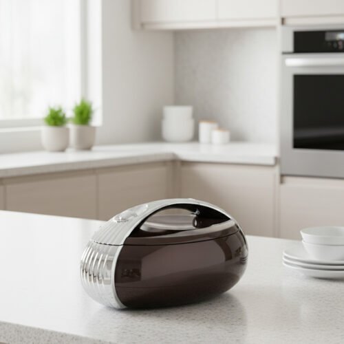 Glossy brown oval insulated hotpot casserole with chrome handle on a modern kitchen countertop.