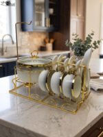 Luxury white ceramic soup tureen set with gold accents, hanging glass lid, matching soup bowls, saucers, and spoons on a gold metal stand.