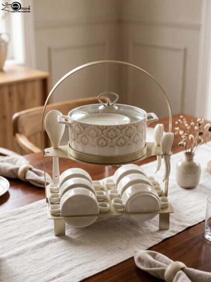 Luxury ceramic soup tureen set featuring a patterned soup pot, soup bowls with handles, matching saucers, spoons, and a gold metal stand on a wooden dining table.
