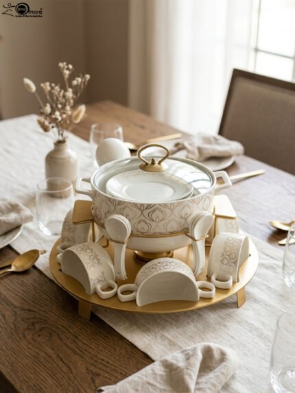 Luxury white ceramic soup tureen set with gold leaf pattern on a metal buffet burner stand with matching bowls and spoons.