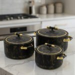 3-piece black marble insulated hot pot casserole set with gold handles on a white marble countertop