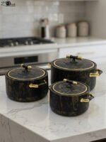 3-piece black marble insulated hot pot casserole set with gold handles on a white marble countertop