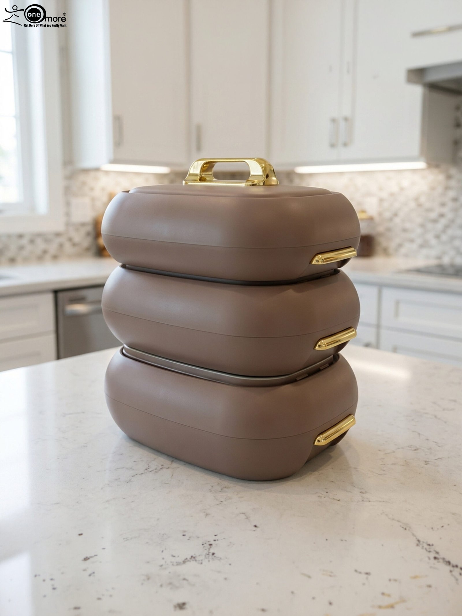 1 Three stacked matte taupe One More insulated hot pots with gold handles on a white kitchen countertop.