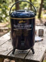 Day Days 9.5 Liter dark blue insulated water cooler jug with spigot tap and tripod legs set on an outdoor picnic table.