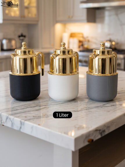 Three One More 1 liter luxury thermal vacuum flasks in black, white, and grey with polished gold tops on a marble kitchen countertop.