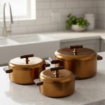 3-piece matte gold thermal hot pot set with dark wooden handles on a marble kitchen countertop