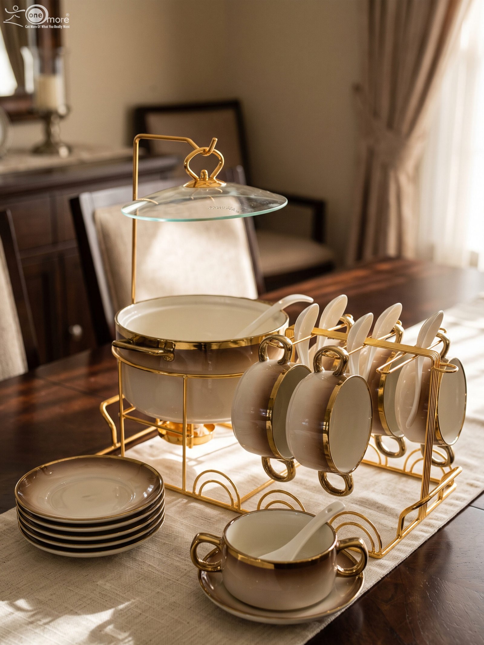 2 Luxury gradient brown ceramic soup tureen pot with glass lid, gold warmer stand, hanging double-handled soup bowls, saucers, and white spoons set on a wooden dining table.