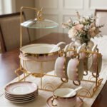Pink and white gradient ceramic soup tureen set with gold rims, suspended glass lid on a gold frame, buffet burner warmer stand, matching soup cups, saucers, and ceramic spoons.