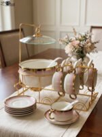 Pink and white gradient ceramic soup tureen set with gold rims, suspended glass lid on a gold frame, buffet burner warmer stand, matching soup cups, saucers, and ceramic spoons.