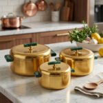 Three-piece luxury brushed gold insulated hot pot set with emerald green handles displayed on a marble kitchen countertop