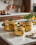 Three-piece luxury brushed gold insulated hot pot set with emerald green handles displayed on a marble kitchen countertop