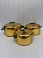 Three-piece luxury brushed gold insulated hot pot set with emerald green handles displayed on a marble kitchen countertop