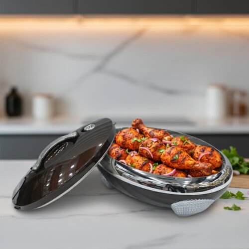 An elegant oval-shaped insulated hotpot in dark brown with a silver stainless steel interior and decorative studded handles, open with the lid resting on a polished wooden dining table.