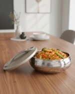 Grey insulated stainless steel hotpot casserole dish with an ornate decorative lid on a modern kitchen countertop