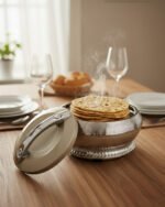 An elegant champagne-colored insulated luxury hotpot casserole with a sparkling crystal rhinestone base and chrome accents, sitting on a dark kitchen countertop.