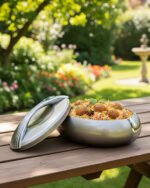 Modern grey insulated hotpot casserole with polished chrome handle on a wooden kitchen countertop