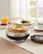 Round dark wood grain insulated hotpot casserole with a sparkling rhinestone base and chrome lid handle on a white kitchen countertop