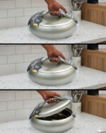 Modern grey insulated hotpot casserole with polished chrome handle on a wooden kitchen countertop