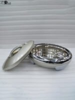 Cream and stainless steel insulated thermal hotpot casserole dish with lid resting on a granite kitchen countertop.