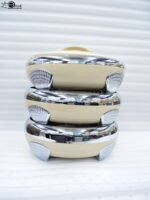 Set of three cream-colored insulated hotpots with polished chrome accents and silver legs on a wooden table.
