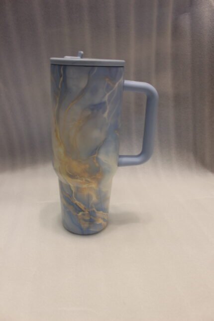 Four 1180ml insulated stainless steel travel tumblers with handles and straws in lavender, peach, blue-gold, and navy marble patterns on a kitchen counter.