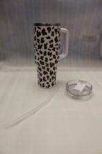 Six 1180ml leopard print insulated travel tumblers with handles and straws displayed in various colors on a kitchen counter.
