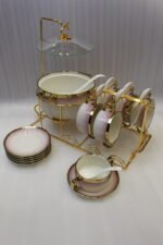 Pink and white gradient ceramic soup tureen set with gold rims, suspended glass lid on a gold frame, buffet burner warmer stand, matching soup cups, saucers, and ceramic spoons.