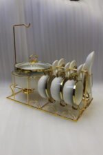 Luxury white ceramic soup tureen set with gold accents, hanging glass lid, matching soup bowls, saucers, and spoons on a gold metal stand.