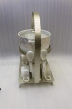 Luxury white and gold geometric pattern ceramic soup tureen set with matching mugs, spoons, and silver metallic rack on a marble kitchen counter
