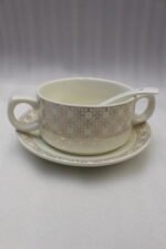 Luxury white and gold geometric pattern ceramic soup tureen set with matching mugs, spoons, and silver metallic rack on a marble kitchen counter