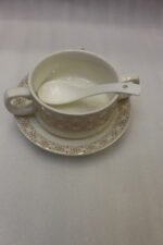 Luxury white and gold geometric pattern ceramic soup tureen set with matching mugs, spoons, and silver metallic rack on a marble kitchen counter