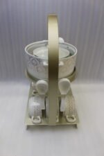 Luxury ceramic soup tureen set featuring a patterned soup pot, soup bowls with handles, matching saucers, spoons, and a gold metal stand on a wooden dining table.