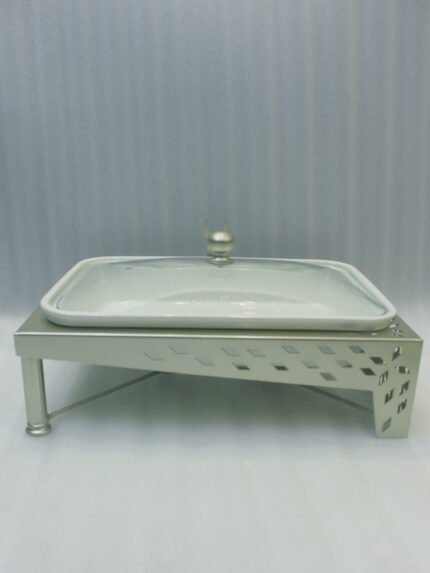 Three ceramic single buffet dishes with clear glass lids and champagne gold stainless steel warming stands displayed on a marble kitchen counter.