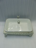 Three ceramic single buffet dishes with clear glass lids and champagne gold stainless steel warming stands displayed on a marble kitchen counter.