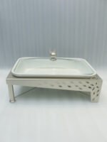 Three rectangular ceramic single buffet dishes with clear glass lids set in champagne gold stands on a kitchen marble countertop.