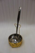Luxury gold and stainless steel round chafing dish buffet server with a glass dome lid suspended on a gold frame, matching ladle, and buffet burner on a kitchen counter.