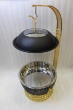One More luxury matte black and gold hanging lid buffet chafing dish with stainless steel pan on a marble kitchen counter.