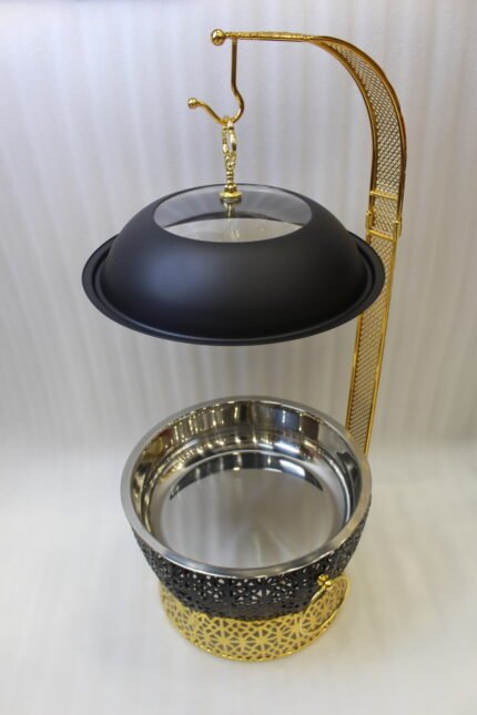 One More luxury matte black and gold hanging lid buffet chafing dish with stainless steel pan on a marble kitchen counter.