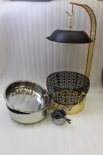 One More luxury matte black and gold hanging lid buffet chafing dish with stainless steel pan on a marble kitchen counter.